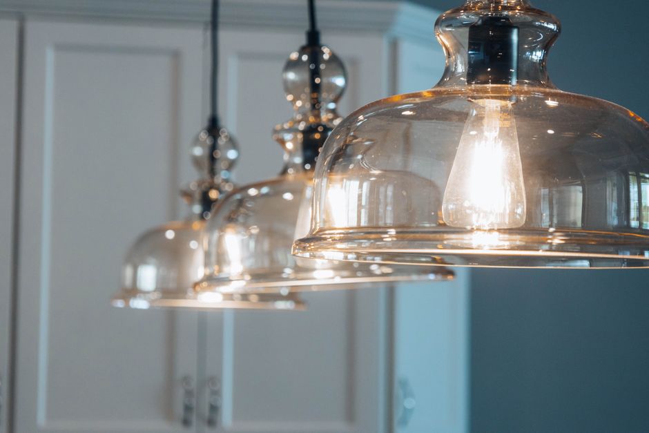 Suspension moderne à trois lampes dans un salon élégant, créant une ambiance chaleureuse et design.